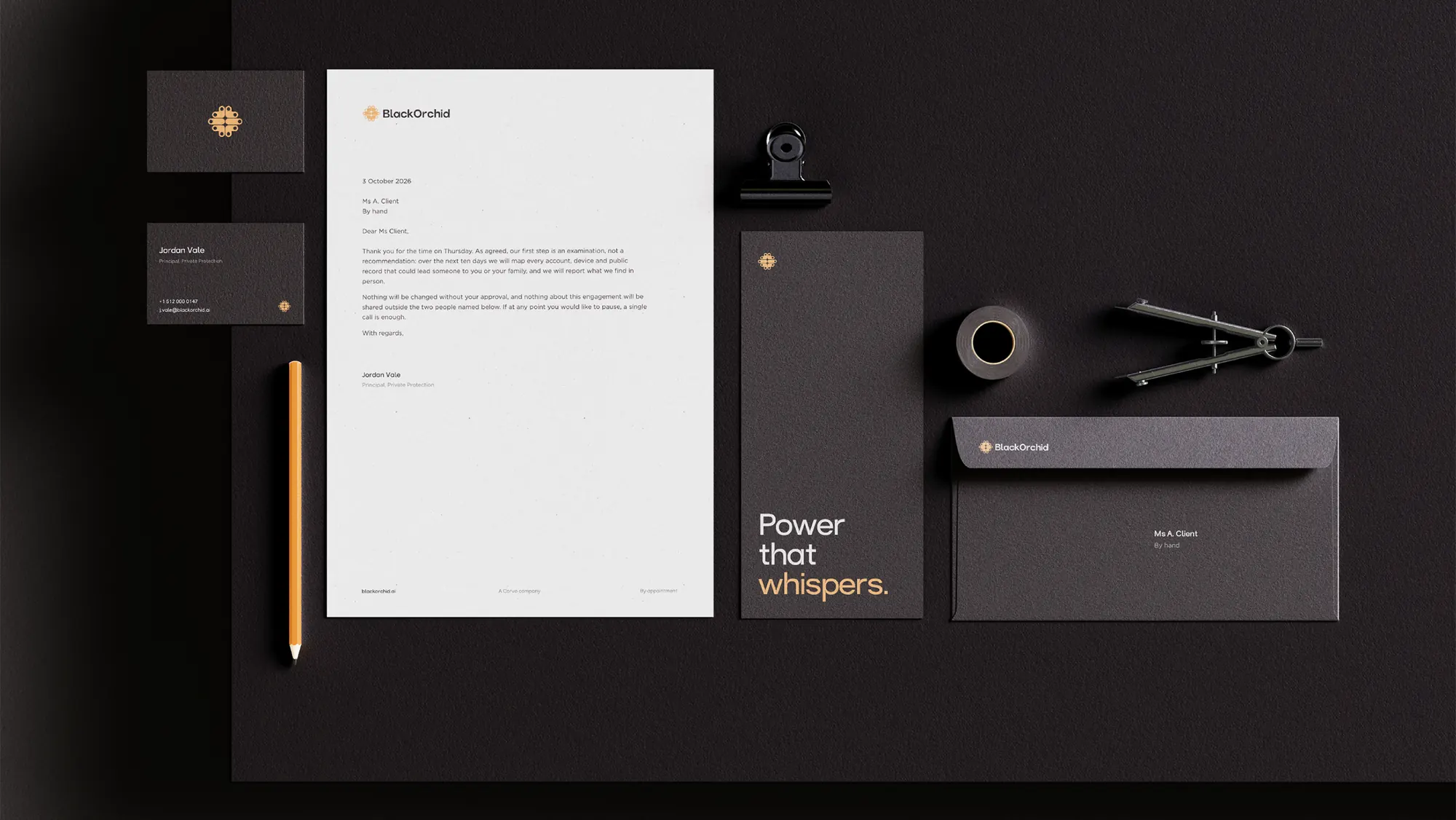 A flat lay on a dark surface: BlackOrchid letterhead, business cards, an envelope, and a card reading Power that whispers, with a pencil and drawing compass.