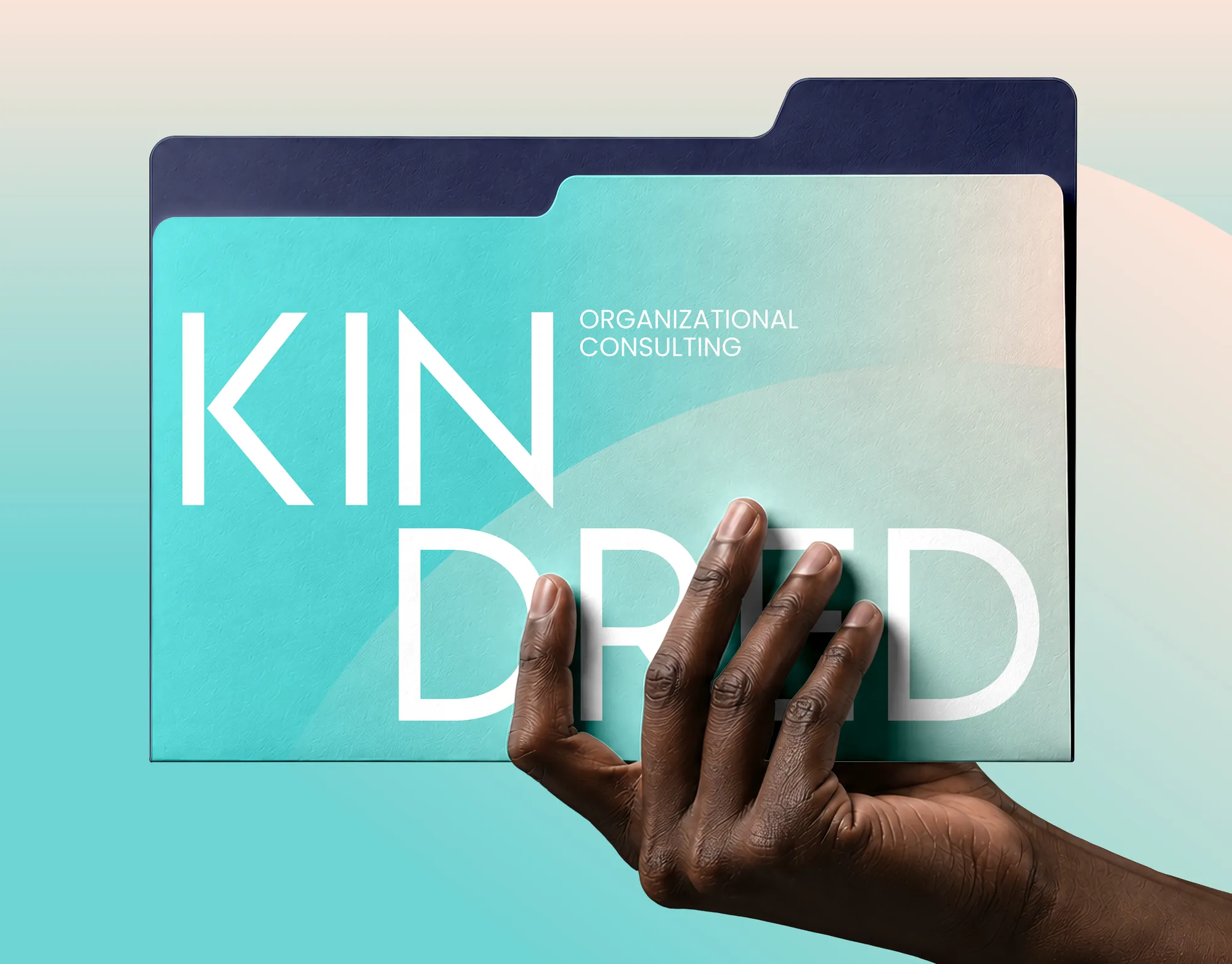 A hand holding a Kindred folder in mist and blush with a navy tab, the wordmark split over two lines as KIN and DRED.